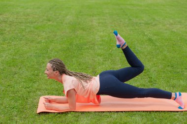 Parktaki paspasın üzerinde egzersiz yapan genç Avrupalı kadın.