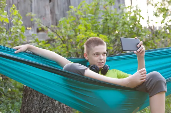 Bir çocuk hamakta oturup arkadaşlarıyla sohbet etmekten zevk alır.