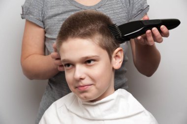 Saç kesme makinesi kullanan sarışın bir çocuğun saç kesimi.