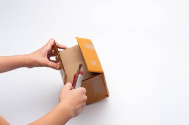 Beyaz arka plandaki paketi açarken insan eli bir bıçak tutuyor.