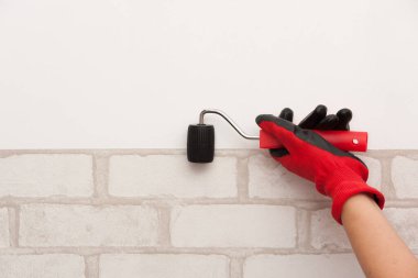 Kırmızı eldivenli bir işçinin eli bir silindir tutuyor. Duvar kağıdı yapıştırma işlemi