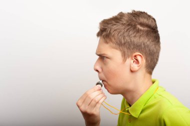 Islık çalan genç bir çocuk spor koçu ya da hakeme benzer.