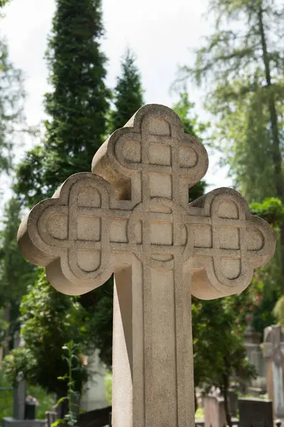 Mezarlıkta taş haçlı güneşli bir mezar.