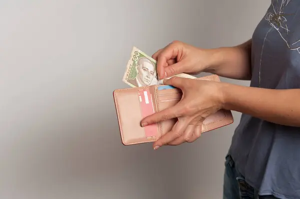 Kadın eli cüzdandan 500 hryvnias çekiyor.