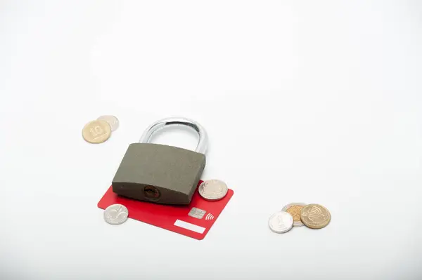 Finans ve ekonomi. Beyaz arka planda asma kilitli kırmızı kredi kartı ve İsrail şekeli paralar.