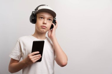 Tablet ve kulaklıklı bir çocuk sıradan bir şekilde poz verir.