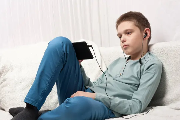 ? çocuk bir tablet ve kulaklık kullanarak internet içeriğini tarıyor