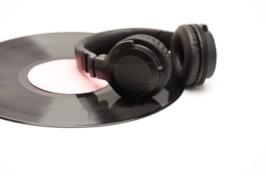 Beyaz arka planda siyah kablosuz kulaklık ve vinil plak.