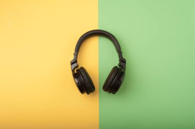 Black wireless headphones on the yellow and green background clipart