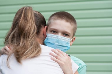 The boy with medical mask hugging his mom clipart