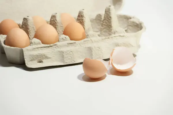 Beyaz arka planda birkaç yumurta ve yumurta kabuğu var.