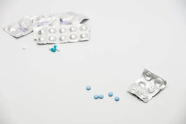 Tıbbi ilaçlar ve haplar beyaz arka plana saçılmış.