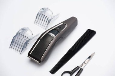 Beyaz arka planda bir kuaför seti olan modern bir kablosuz teknoloji kırpıcısı.