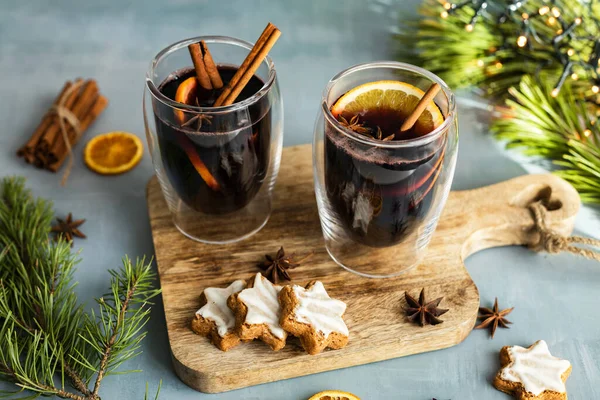 Hot winter drink mulled wine with spices and fresh orange slices in New Years decorations. Traditional winter drink