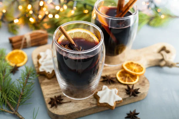 Hot winter drink mulled wine with spices and fresh orange slices in New Years decorations. Traditional winter drink