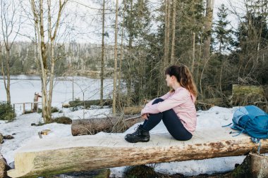 Bir bankta oturan ve ormanda yürürken dinlenen bir kızın portresi. Yürüyüş. Etkin yaşam biçimi.