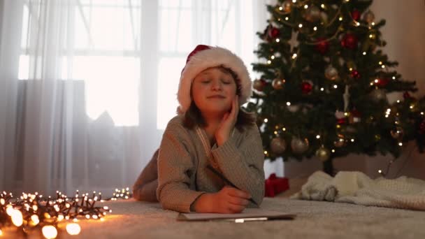 Niña Escribe Una Carta Santa Claus Lado Del Árbol Navidad — Vídeo de stock
