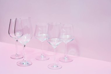 Pembe zemin üzerinde çeşitli boş şarap kadehleri ve metin için boşluk