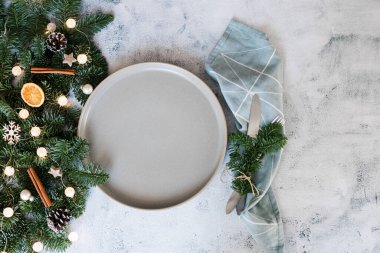 Yılbaşı ya da yeni yıl sofrası seramik tabakla süslenmiş, köknar dalı dekor ve çatal bıçaklı. Yukarıdan bak. Boşluğu kopyala. 