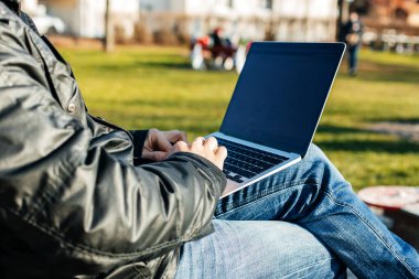 Sokakta dizüstü bilgisayarla çalışan, bankta oturan bir adamın elleri. Uzak çalışma konsepti.