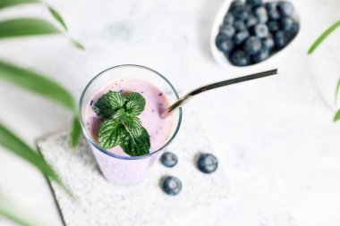 Blueberry smoothie in a glass on the table. Ideal for vegetarian breakfast, diets and detox. 