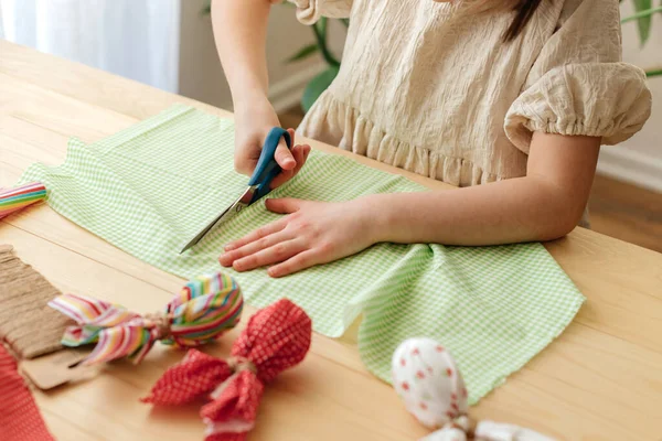 Making Easter eggs in the shape of a hare from textile. The girl prepares the fabric, cuts it with scissors. Home decoration for Easter.