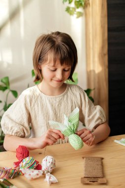 Making Easter decorations. A girl makes a textile Easter egg at home in the shape of a bunny, bunny. home decoration.