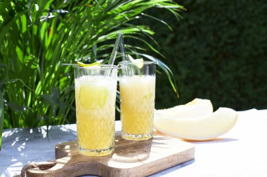 Refreshing melon smoothie with ice and lime in the sun. Summer cooling drinks