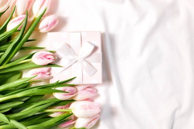 Taze pembe lalelerden oluşan bir buket ve sabah yatağın üstünde bir hediye kutusu. Sevgililer günü ya da kadınlar günü hediyesi..