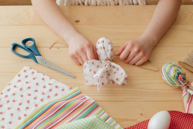 Close-up of a girls hands at home making easter egg decorations in the shape of a rabbit from cloth. Ideas for decorating your home for Easter