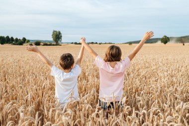 Mutlu çocuk ve kız çavdardan kulaklarla bir tarlada durup el ele tutuşuyorlar. Tatilde mutlu ve özgür çocuklar. Tatil kavramı