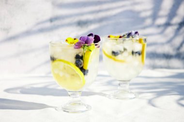 Limonlu soğuk limonata ve yenilebilir çiçekler. Sağlıklı yaz içkileri ve kokteyller. Detoks suyu. 