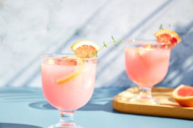Taze greyfurt suyuyla soğuk kokteyller, kekik ve taze meyve dilimleriyle servis ediliyor. Turunçgil meyveli yaz kokteylleri