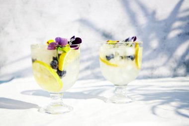 Limonlu soğuk limonata ve yenilebilir çiçekler. Sağlıklı yaz içkileri ve kokteyller. Detoks suyu. 
