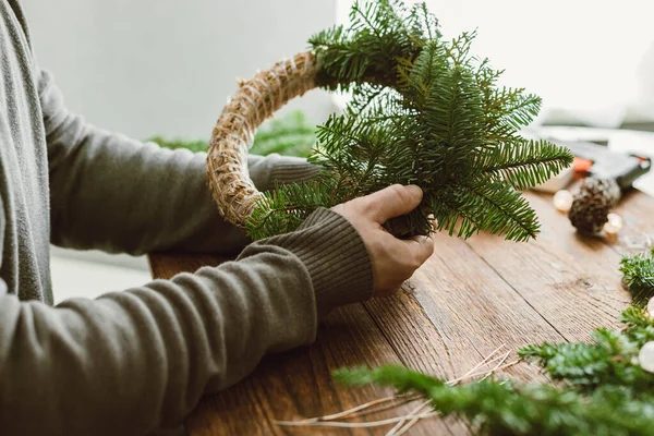 stock image A man at home makes a Christmas wreath from fresh spruce branches. Decorating your home for the holidays