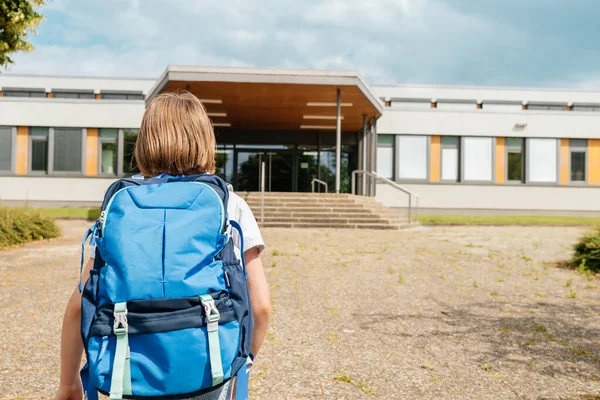 A schoolgirl girl with a school backpack on her back runs to school. Children are excited about the beginning of the school year and are happy to go to classes.