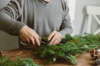 Erkek bir çiçekçinin elleri taze ladin dalları, koniler ve kurutulmuş meyvelerle ıslatarak yeni yıl kutluyor. Yeni yıl ana sınıfı..