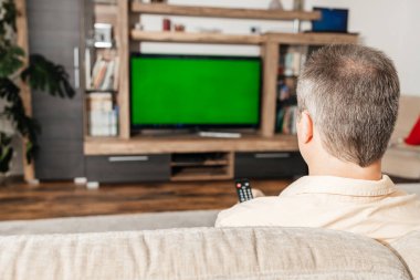 Kanepede oturan ve boş zamanlarında televizyon izleyen bir adam.. 