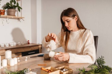 Genç bir kadın evinde kendi elleriyle yılbaşı süsü istiyor. Bir kız Noel süsü, tarçın çubukları ve taze yeşil dallarla el yapımı mumlar süslüyor. Yeni yılı bekliyorum.