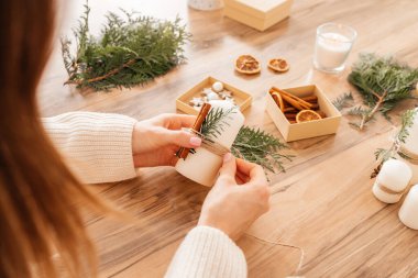 Noel ve Yeni Yıl için dekorasyon hazırlayan bir kız eli. El yapımı hediyeler. Tatil için ev dekorasyonu. Mum dekorasyonu
