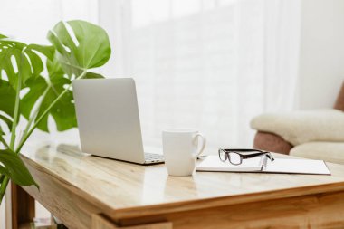 The laptop is on the table next to glasses, a notepad and a cup of coffee. A workspace at home. Distant work. 