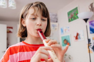 Genç bir kız evinde müzik aleti çalıyor, flüt, odasında. Evde müzik dersleri. Gençlerin hobileri..