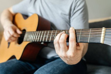 Adam oturur, gitar çalar, akor çalar, çalmayı öğrenir. Yetişkinler için hobiler.