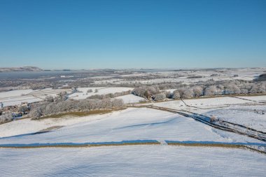 İngiltere 'nin Burnley kasabasındaki Mereclough kasabasının insansız hava aracı fotoğrafı İngiltere' de kar yağışlı bir kış gününde tarlaları ve mavi gökyüzünü gösteriyor..
