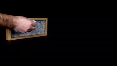6 Şubat tarihini gösteren tahta bir takvim bloğu. Üzerinde tarih ve ay yazılı metal diskleri çıkartan bir adam elini takıyor.