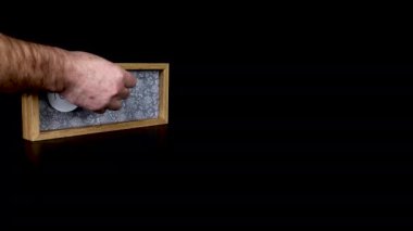 Tahta takvim bloğu 9 Şubat 'ta bir adamın elini takıp üzerinde tarih ve ay yazılı metal diskleri çıkardığını gösteriyor.