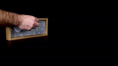 7 Şubat tarihini gösteren tahta bir takvim bloğu. Üzerinde tarih ve ay yazılı metal diskleri çıkartan bir adam eli takıyor.