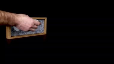 22 Şubat tarihini gösteren ahşap bir takvim bloğu. Üzerinde tarih ve ay yazılı metal diskleri çıkartan bir adam elini takıyor.