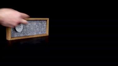 Tarihi gösteren tahta bir takvim bloğu. 25 Şubat 'ta, üzerinde tarih ve ay yazılı metal diskleri çıkartan bir adam elini takıyor.