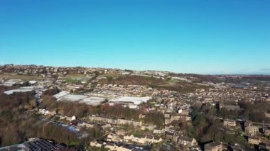 Aerial drone footage of the village of Golcar in West Yorkshire, England, Huddersfield in the UK showing the residential houses estates in the winter time with small patches of snow on the ground.